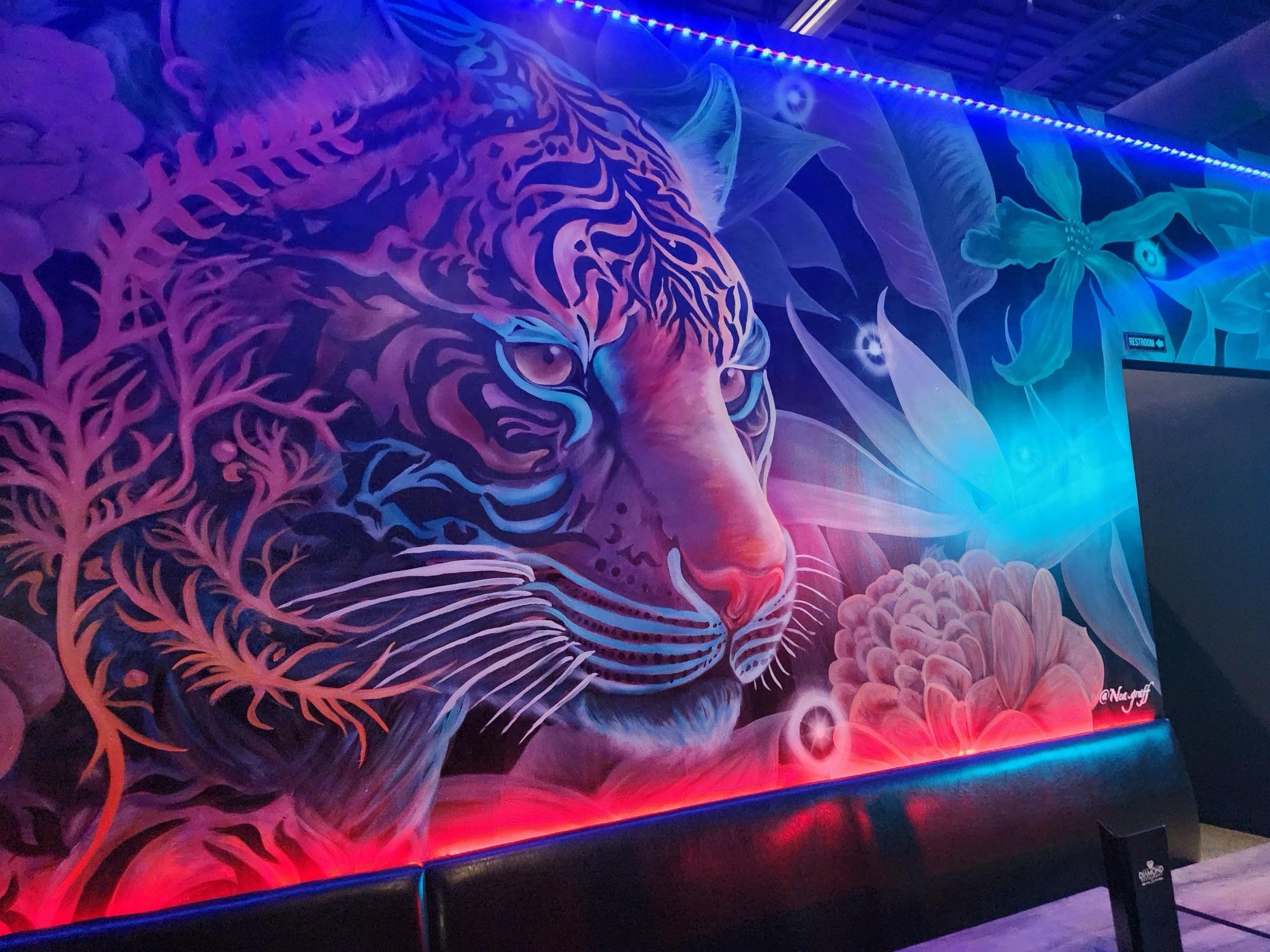Neon-lit interior mural of a tiger among tropical plants