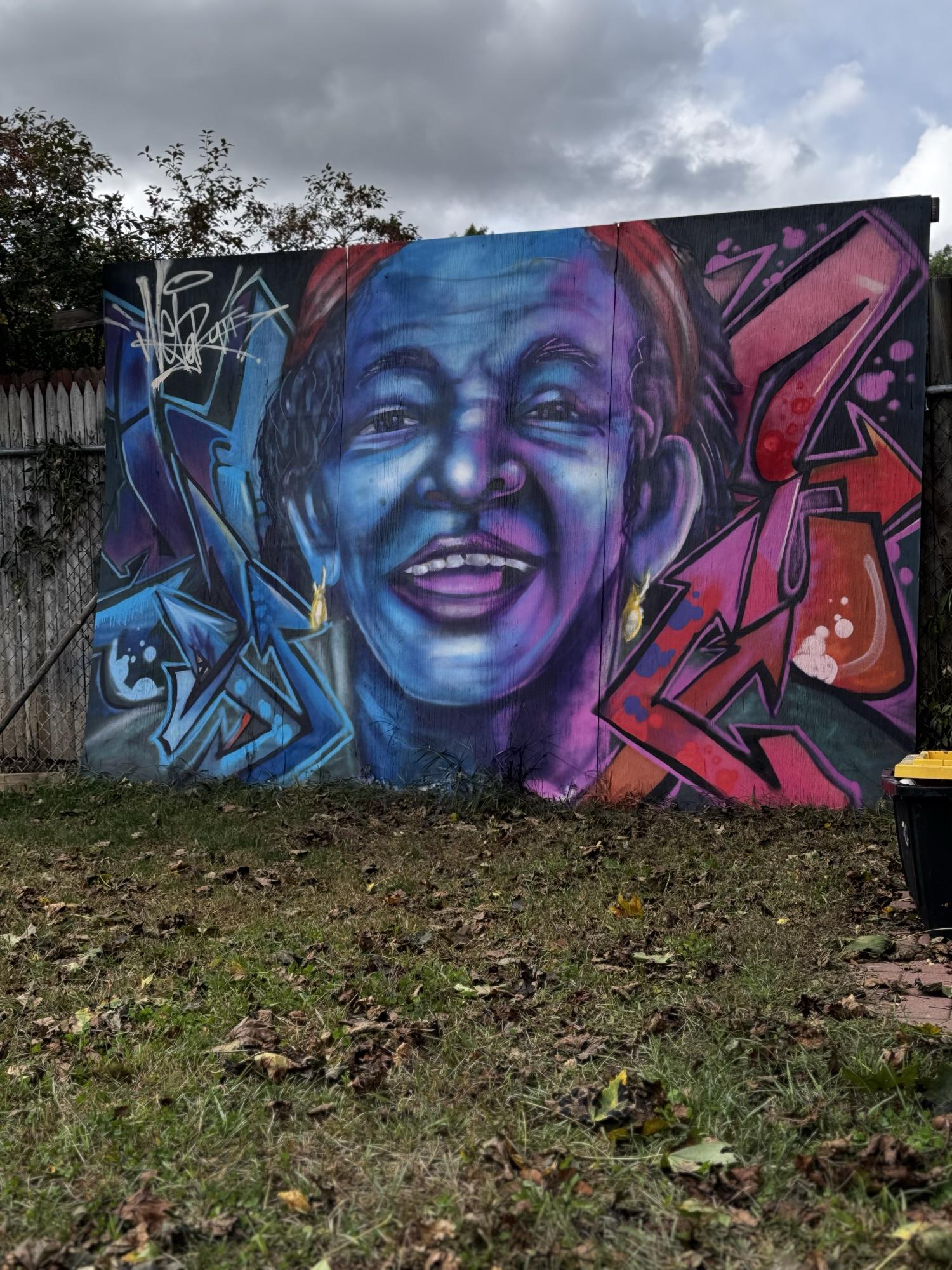 Graffiti piece of a smiling face in blue with wildstyle letters