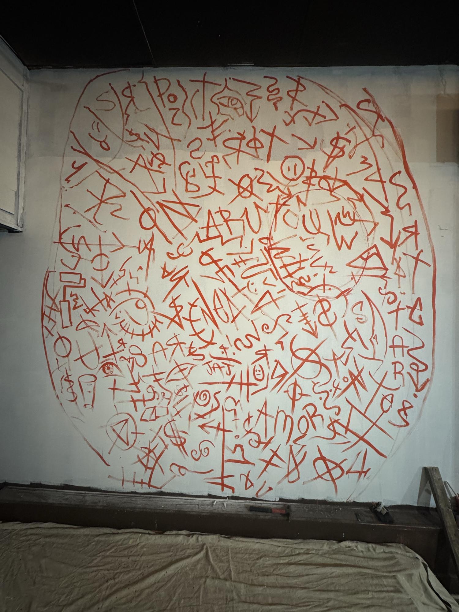 Wall covered in red hand-painted lettering in a circular composition